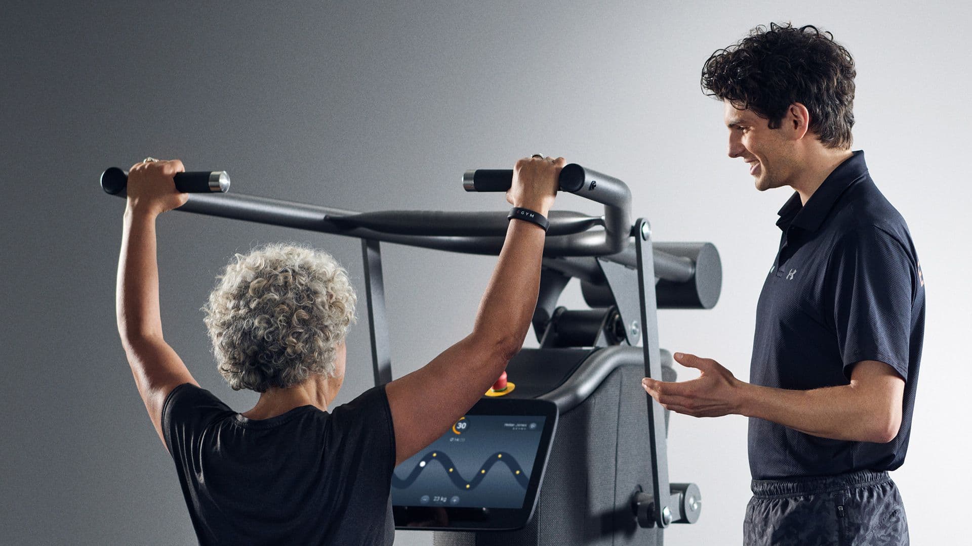 Trainer betreut eine Kundin an einem EGYM-Trainingsgerät